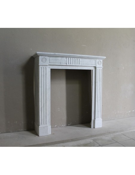 Charming Neoclassical antique fireplace in white marble, featuring refined floral sculptural details.