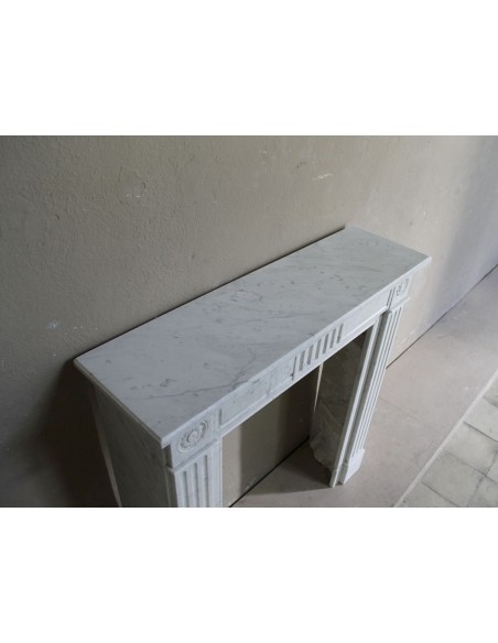 Charming Neoclassical antique fireplace in white marble, featuring refined floral sculptural details.