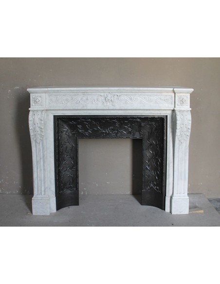 Antique Neoclassical white marble fireplace with floral decorations and “snail” elements, with its original cast iron insert.
