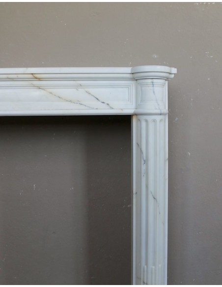 Antique neoclassical marble fireplace mantel with golden veins on a white background. A truly elegant white marble mantel