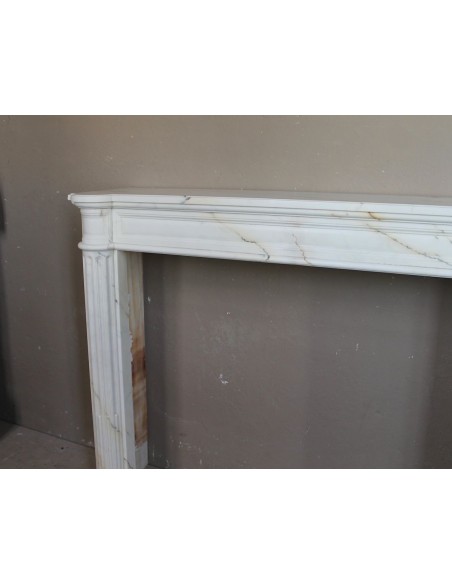 Antique neoclassical marble fireplace mantel with golden veins on a white background. A truly elegant white marble mantel