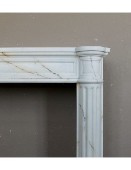 Antique neoclassical marble fireplace mantel with golden veins on a white background. A truly elegant white marble mantel