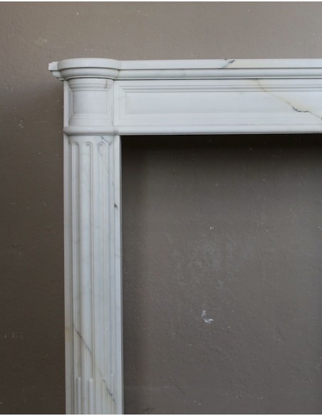 Antique neoclassical marble fireplace mantel with golden veins on a white background. A truly elegant white marble mantel
