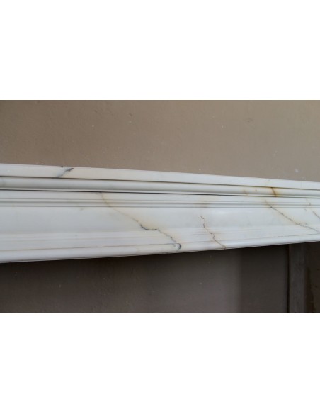 Antique neoclassical marble fireplace mantel with golden veins on a white background. A truly elegant marble fire surround.