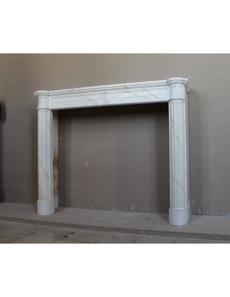 Antique neoclassical marble fireplace mantel with golden veins on a white background. A truly elegant white marble mantel