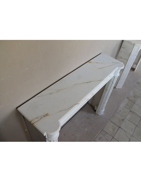 Antique neoclassical marble fireplace mantel with golden veins on a white background. A truly elegant white marble mantel