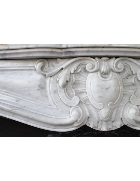Louis XV “Moustache” fireplace mantel in White Carrara marble and fitted with its original cast iron insert.