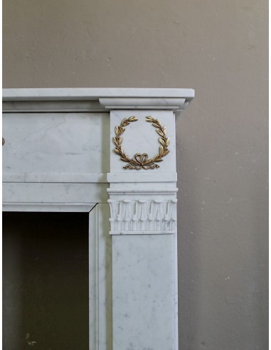 Antique neoclassical mantel carved in White marble with gilded bronzes depicting olive leaves and lions.