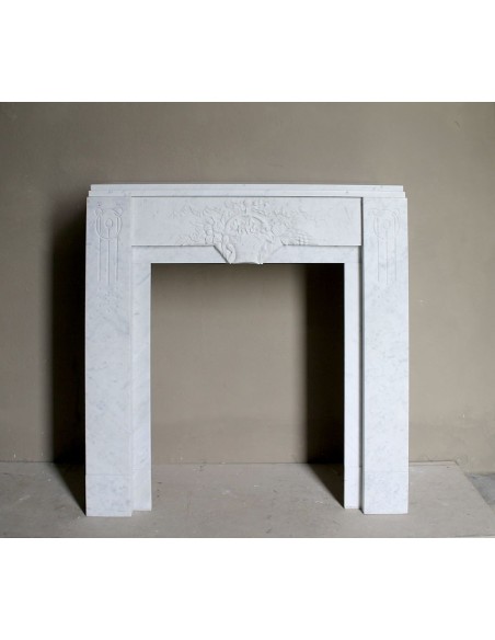 Antique genuine Art Deco mantelpiece, with iconic architecture and floral decorations, carved in white Carrara marble.