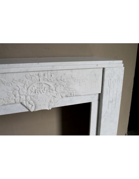 Antique genuine Art Deco mantelpiece, with iconic architecture and floral decorations, carved in white Carrara marble.