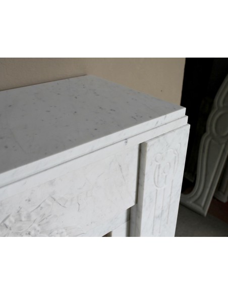 Antique genuine Art Deco mantelpiece, with iconic architecture and floral decorations, carved in white Carrara marble.
