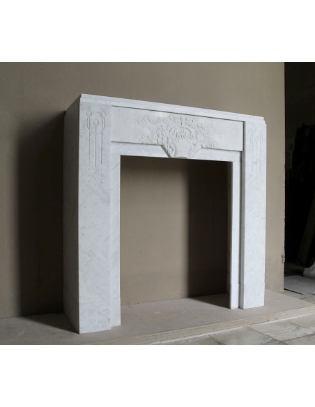 Antique genuine Art Deco mantelpiece, with iconic architecture and floral decorations, carved in white Carrara marble.