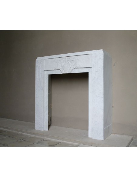 Antique genuine Art Deco mantelpiece, with iconic architecture and floral decorations, carved in white Carrara marble.