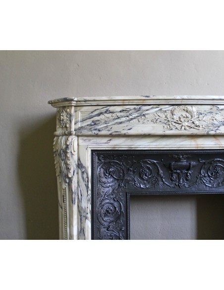 Neoclassical mantelpiece in veined Statuary marble with tones from white to beige to violet, with its original cast iron insert.