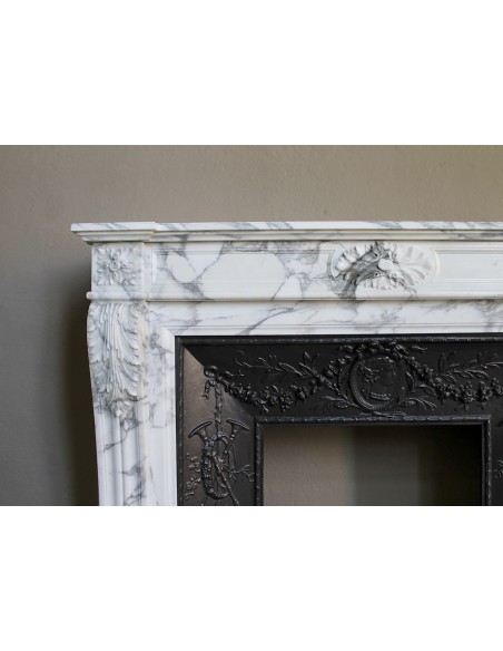 Neoclassical “Trois Fleurs” fireplace mantel in white veined marble, provided with its original cast iron insert.