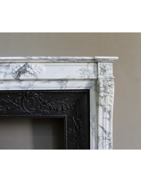 Neoclassical “Trois Fleurs” fireplace mantel in white veined marble, provided with its original cast iron insert.