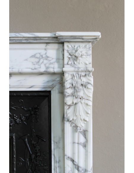 Neoclassical “Trois Fleurs” fireplace mantel in white veined marble, provided with its original cast iron insert.
