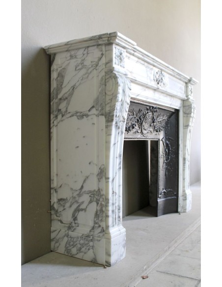 Neoclassical “Trois Fleurs” fireplace mantel in white veined marble, provided with its original cast iron insert.
