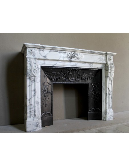 Neoclassical “Trois Fleurs” fireplace mantel in white veined marble, provided with its original cast iron insert.
