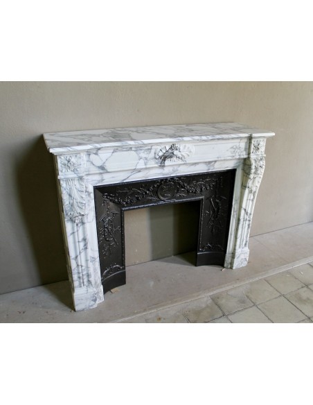 Neoclassical “Trois Fleurs” fireplace mantel in white veined marble, provided with its original cast iron insert.