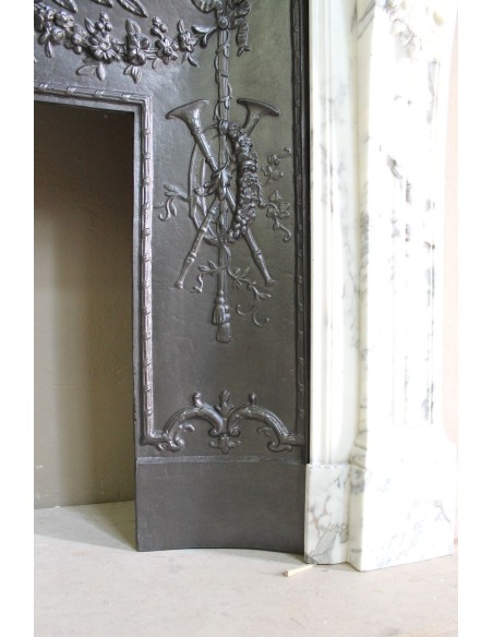 Neoclassical “Trois Fleurs” fireplace mantel in white veined marble, provided with its original cast iron insert.