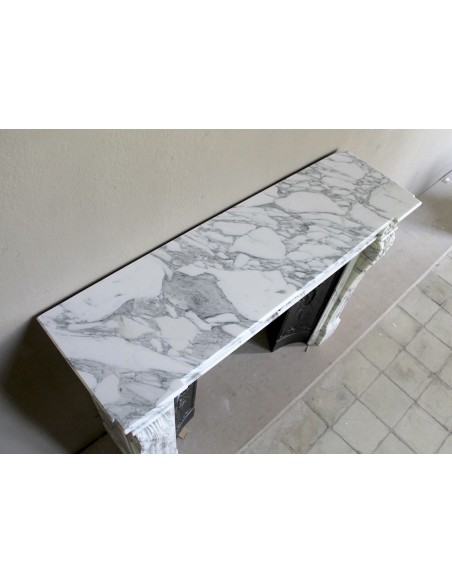 Neoclassical “Trois Fleurs” fireplace mantel in white veined marble, provided with its original cast iron insert.