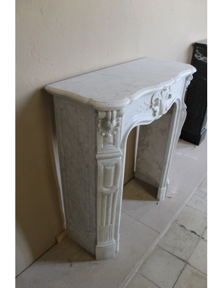 Extremely rare baroque fireplace of very small dimensions and significant decorative carvings in white Carrara marble.