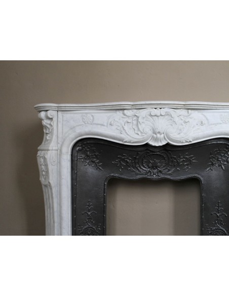 Antique Louis XV fireplace mantel in white marble with elegant floral decorations, with its original artistic cast-iron insert