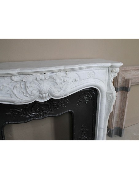 Antique Louis XV fireplace mantel in white marble with elegant floral decorations, with its original artistic cast-iron insert