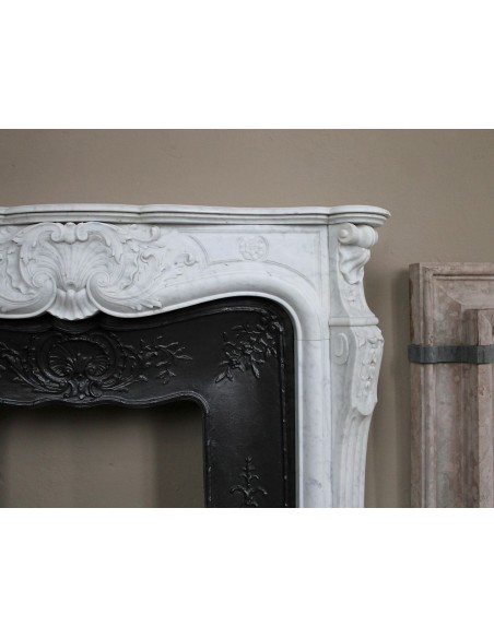 Antique Louis XV fireplace mantel in white marble with elegant floral decorations, with its original artistic cast-iron insert