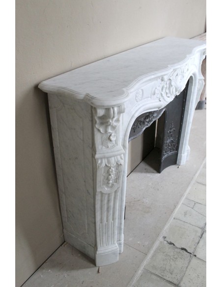 Antique Louis XV fireplace mantel in white marble with elegant floral decorations, with its original artistic cast-iron insert