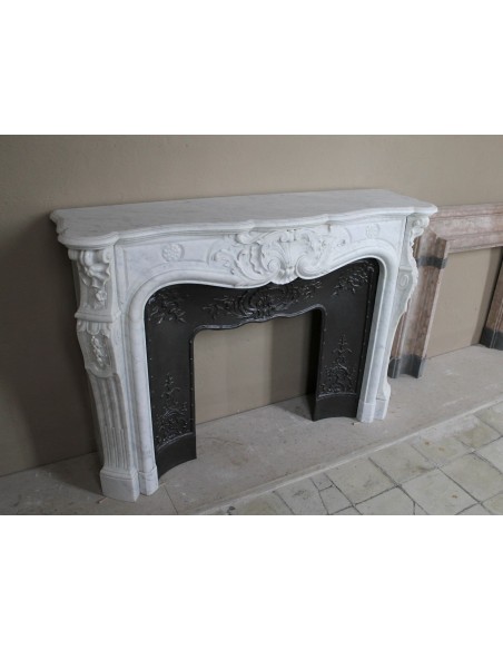 Antique Louis XV fireplace mantel in white marble with elegant floral decorations, with its original artistic cast-iron insert
