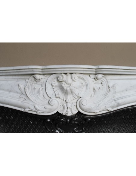 Louis XV “Moustache” fire surround in “Pure White" Carrara marble, complete with cast iron insert featuring floral decorations.