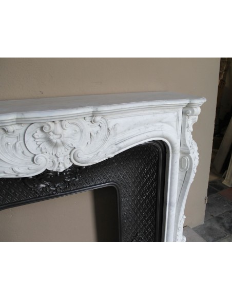 Louis XV “Moustache” fire surround in “Pure White" Carrara marble, complete with cast iron insert featuring floral decorations.