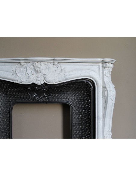 Louis XV “Moustache” fire surround in “Pure White" Carrara marble, complete with cast iron insert featuring floral decorations.