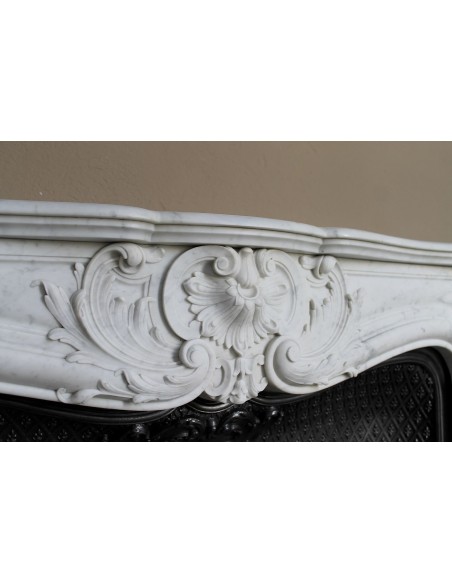 Louis XV “Moustache” fire surround in “Pure White" Carrara marble, complete with cast iron insert featuring floral decorations.