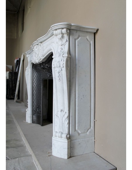 Louis XV “Moustache” fire surround in “Pure White" Carrara marble, complete with cast iron insert featuring floral decorations.