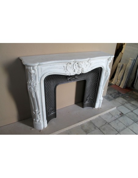 Louis XV “Moustache” fire surround in “Pure White" Carrara marble, complete with cast iron insert featuring floral decorations.