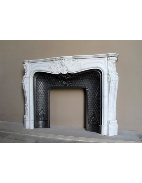 Louis XV “Moustache” fire surround in “Pure White" Carrara marble, complete with cast iron insert featuring floral decorations.