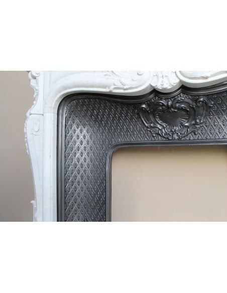 Louis XV “Moustache” fire surround in “Pure White" Carrara marble, complete with cast iron insert featuring floral decorations.