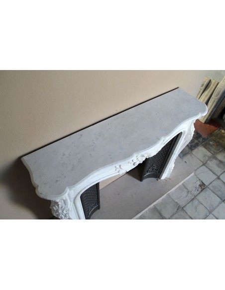 Louis XV “Moustache” fire surround in “Pure White" Carrara marble, complete with cast iron insert featuring floral decorations.