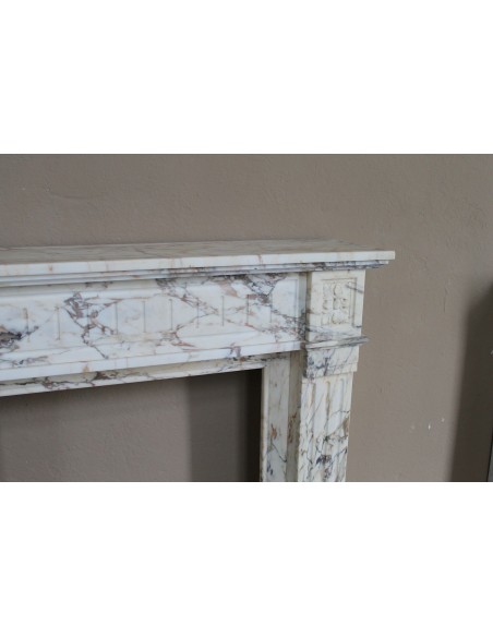Small and lovely antique Neoclassical fireplace mantel in Calacatta Gold marble, with floral decorations and fluted detailing.