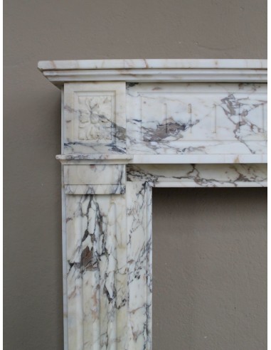 Small and lovely antique Neoclassical fireplace mantel in Calacatta Gold marble, with floral decorations and fluted detailing.