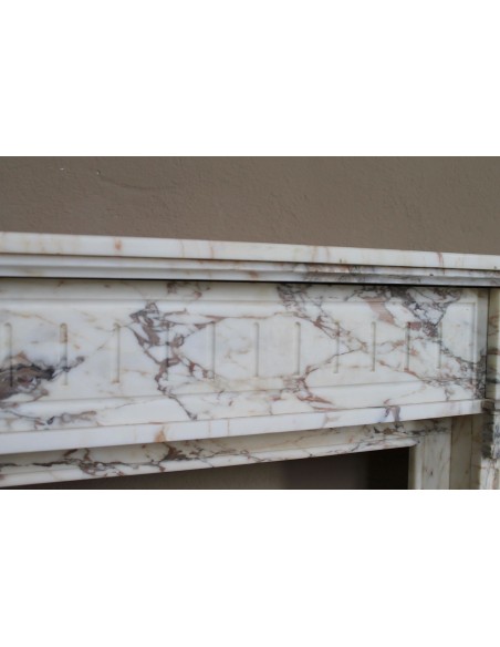 Small and lovely antique Neoclassical fireplace mantel in Calacatta Gold marble, with floral decorations and fluted detailing.