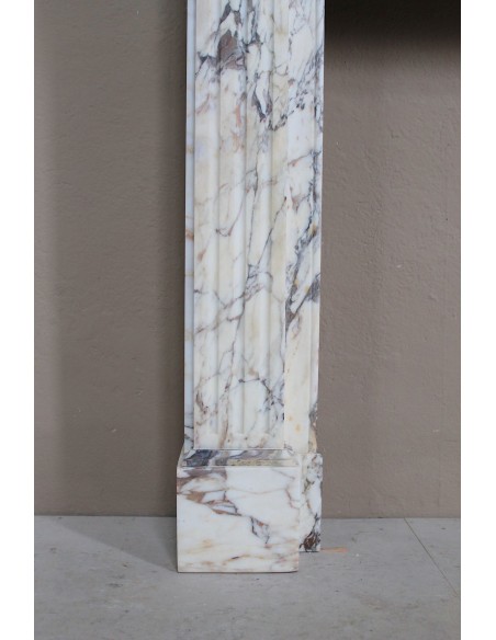 Small and lovely antique Neoclassical fireplace mantel in Calacatta Gold marble, with floral decorations and fluted detailing.