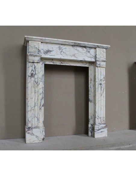 Small and lovely antique Neoclassical fireplace mantel in Calacatta Gold marble, with floral decorations and fluted detailing.