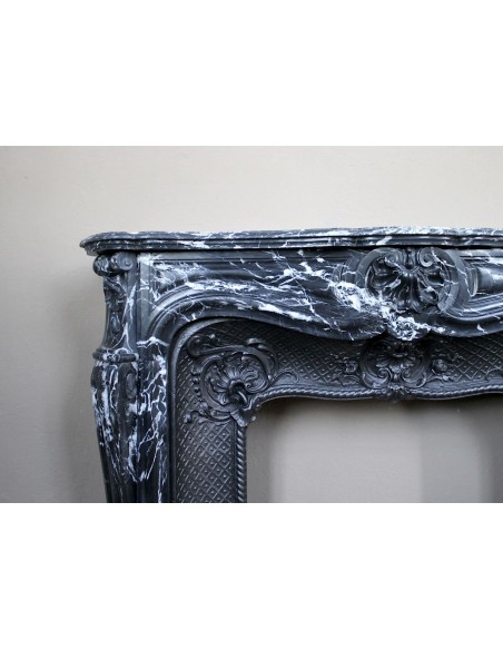 Antique Baroque-style fireplace mantel carved in black Marquinia marble with white veining, with its original cast iron insert.