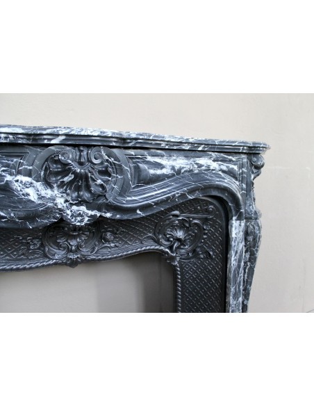 Antique Baroque-style fireplace mantel carved in black Marquinia marble with white veining, with its original cast iron insert.