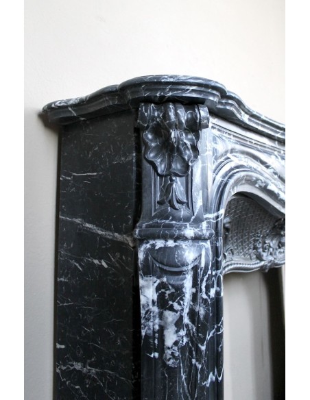 Antique Baroque-style fireplace mantel carved in black Marquinia marble with white veining, with its original cast iron insert.