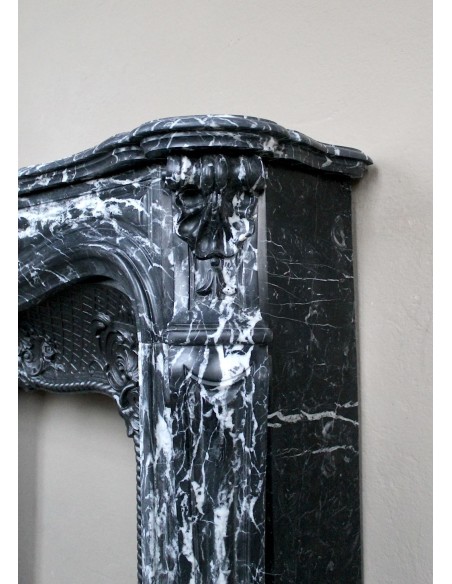 Antique Baroque-style fireplace mantel carved in black Marquinia marble with white veining, with its original cast iron insert.